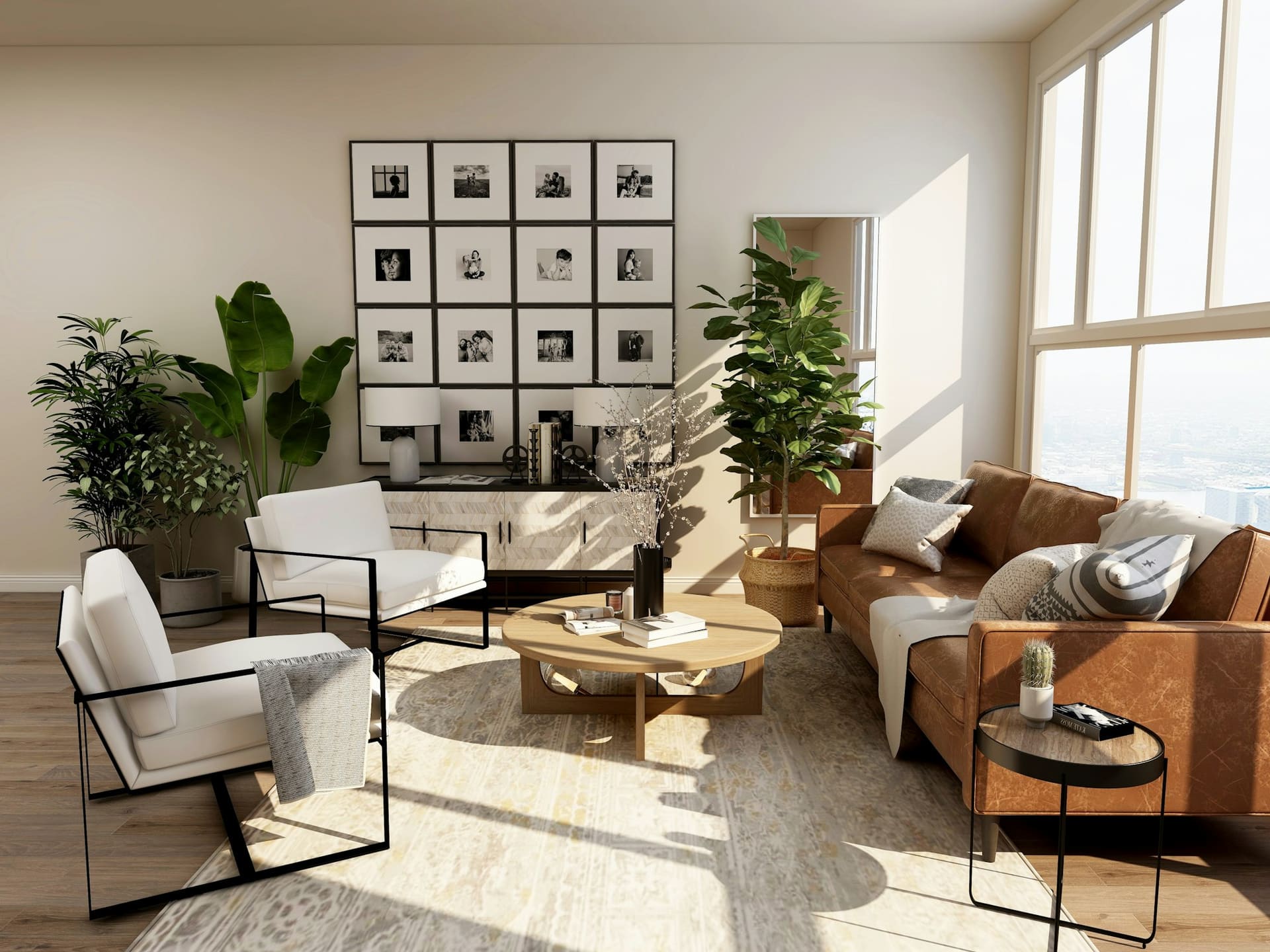 A sunlit living room with a cognac leather sofa, a white lounge chair, a low round table and a grid of framed prints.