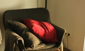 A red pillow on a gray chair.