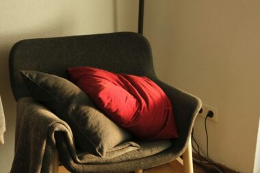 A red pillow on a gray chair.