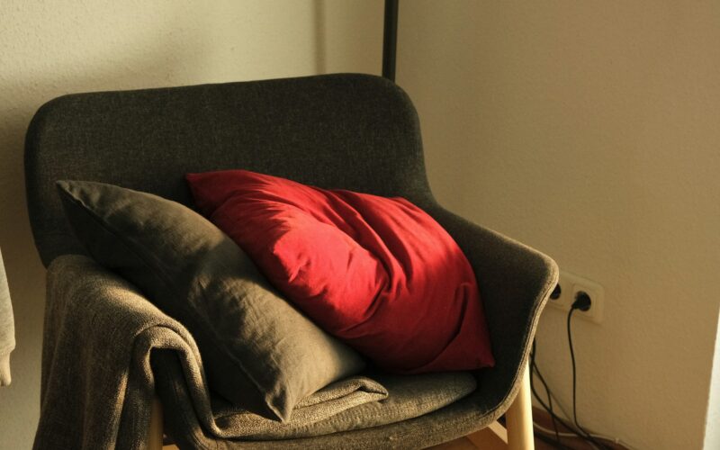 A red pillow on a gray chair.